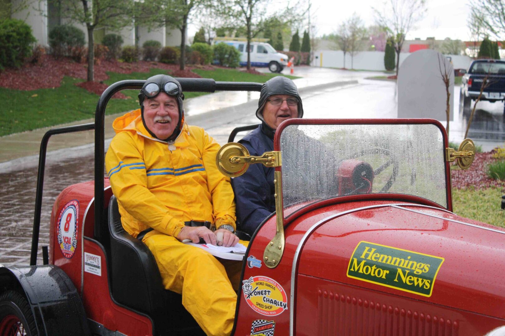 two elderly men riding a vintage car while raining